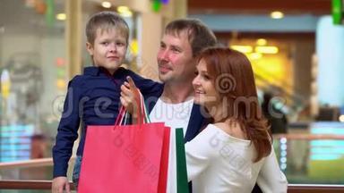 父母在贸易商场和儿子说话。 这家人在购物中心为圣诞节买东西。 快乐的父母